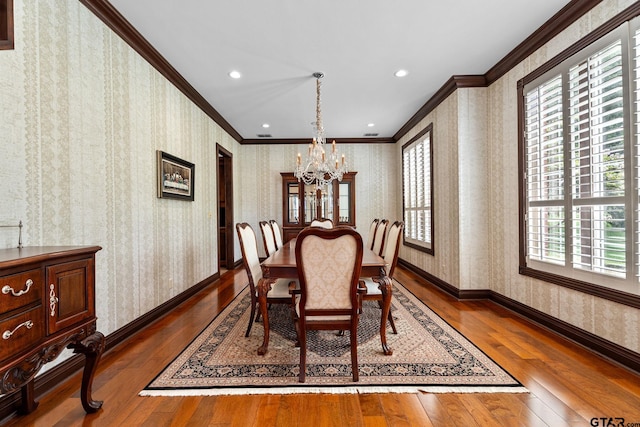 dining area with a notable chandelier, ornamental molding, and dark hardwood / wood-style floors