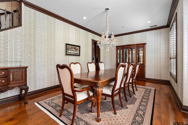 dining room featuring dark wood-type flooring, ornamental molding, and an inviting chandelier