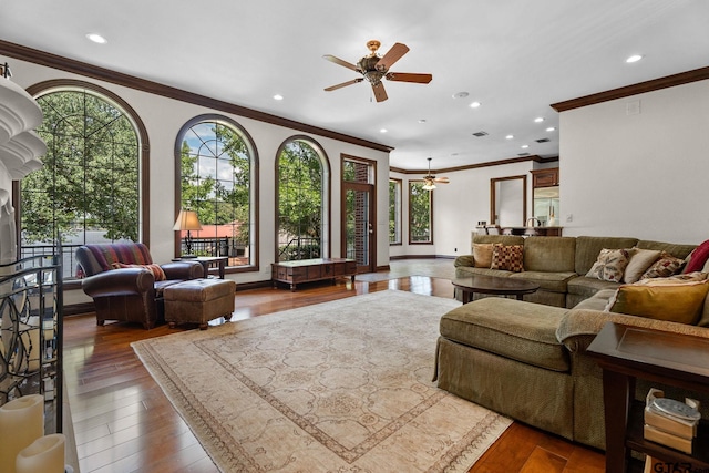 living room with wood-type flooring, crown molding, and ceiling fan