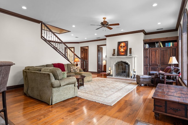 living room with hardwood / wood-style flooring, ceiling fan, and crown molding