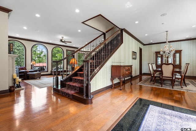 interior space featuring hardwood / wood-style flooring, crown molding, and ceiling fan with notable chandelier