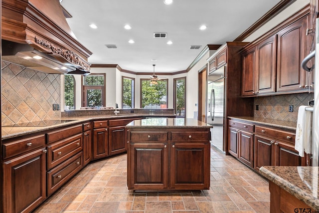 kitchen featuring sink, premium range hood, dark brown cabinets, a center island, and built in fridge