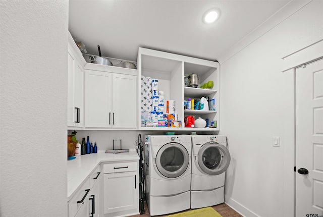 laundry room with ornamental molding, cabinets, and washer and dryer