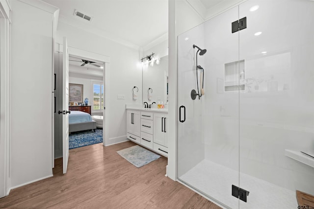 bathroom with ceiling fan, wood-type flooring, vanity, an enclosed shower, and crown molding