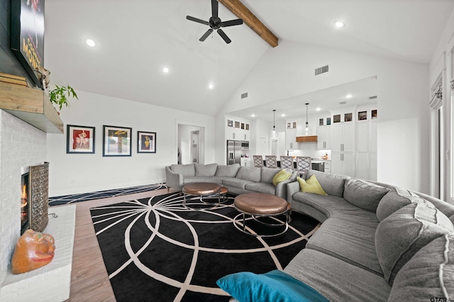 living room featuring ceiling fan, beam ceiling, high vaulted ceiling, a fireplace, and wood-type flooring