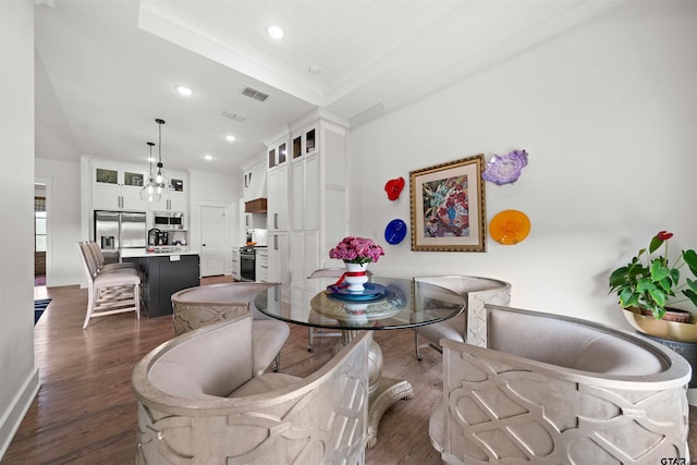 dining area with dark wood-type flooring, a raised ceiling, and a notable chandelier