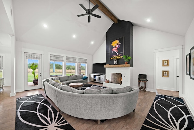 living room with hardwood / wood-style flooring, beamed ceiling, ceiling fan, high vaulted ceiling, and a fireplace