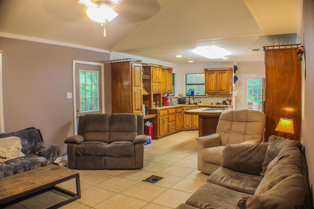 tiled living room featuring ceiling fan, lofted ceiling, and ornamental molding