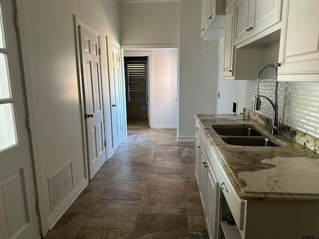 kitchen featuring tasteful backsplash, stone counters, sink, and white cabinets