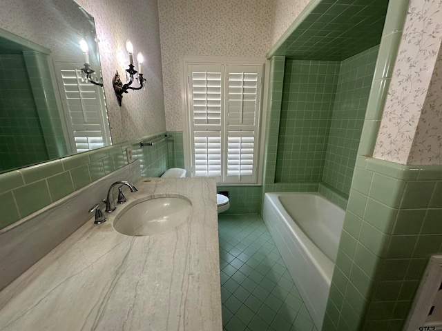 bathroom with tile walls, a bath, toilet, and vanity