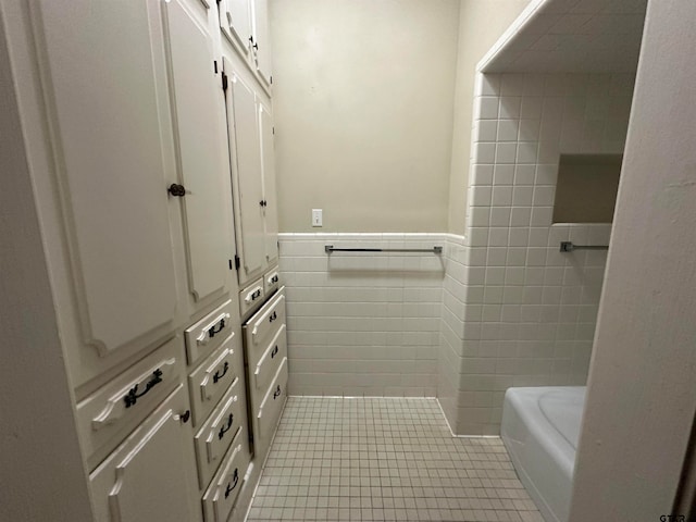 bathroom featuring tile patterned flooring, tile walls, and a washtub