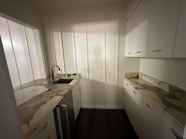 kitchen featuring dark wood-type flooring, sink, light stone counters, and white cabinets