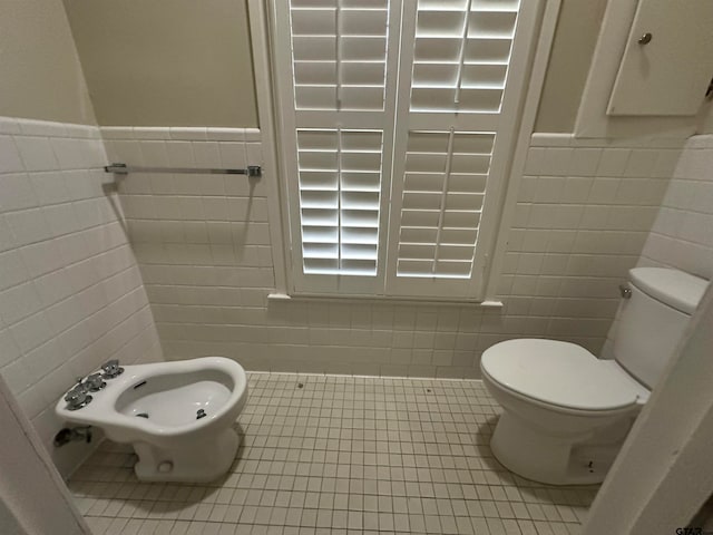 bathroom with a bidet, tile patterned floors, toilet, and tile walls