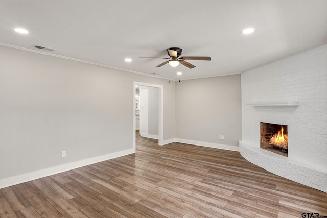 unfurnished living room featuring crown molding, hardwood / wood-style floors, ceiling fan, and a fireplace