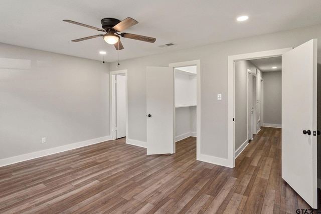 unfurnished bedroom with hardwood / wood-style flooring, ceiling fan, a spacious closet, and a closet