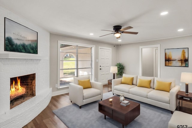 living room featuring crown molding, a brick fireplace, ceiling fan, and dark hardwood / wood-style flooring