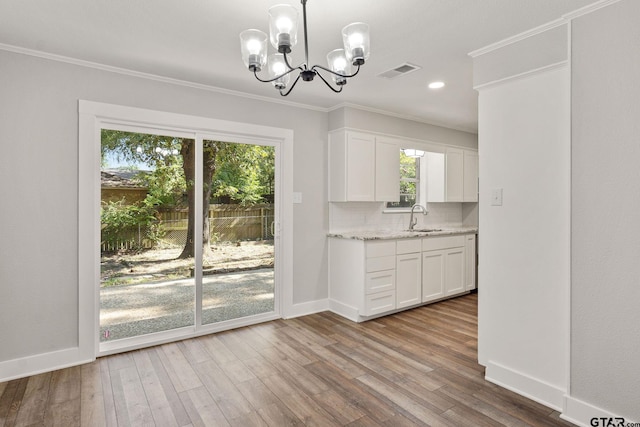 kitchen featuring sink, hanging light fixtures, ornamental molding, white cabinets, and backsplash