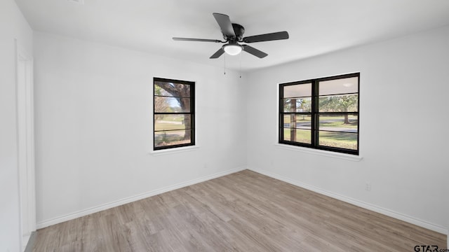 empty room with ceiling fan, plenty of natural light, and light hardwood / wood-style flooring