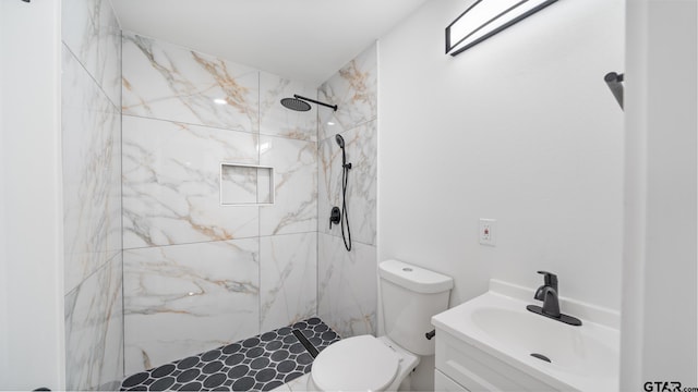 bathroom featuring tiled shower, vanity, and toilet