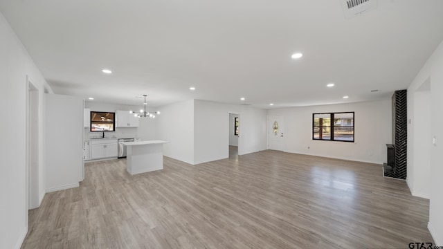 unfurnished living room with a chandelier, light hardwood / wood-style floors, and sink