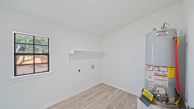 laundry area with electric dryer hookup, a healthy amount of sunlight, light hardwood / wood-style flooring, and water heater