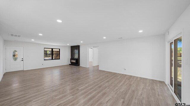 unfurnished living room featuring a wealth of natural light and light hardwood / wood-style flooring