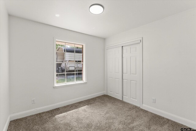 2002 Friendly Ave, Mount Pleasant, TX 75455 - unfurnished bedroom featuring carpet floors, baseboards, and a closet