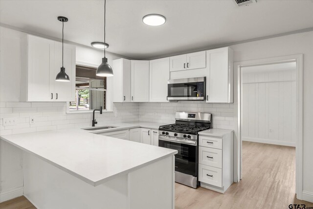 2002 Friendly Ave, Mount Pleasant, TX 75455 - kitchen featuring stainless steel appliances, a sink, a peninsula, decorative backsplash, and white cabinetry