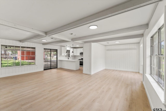 2002 Friendly Ave, Mount Pleasant, TX 75455 - unfurnished living room featuring light wood-style floors, baseboards, and beamed ceiling