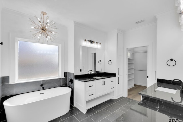 bathroom featuring vanity, a washtub, a chandelier, and ornamental molding