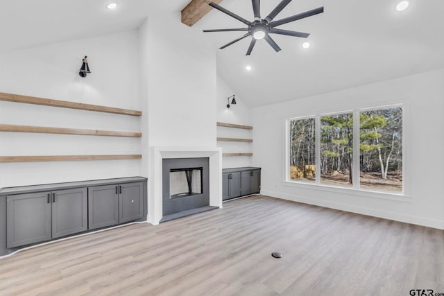 unfurnished living room with light wood-type flooring, ceiling fan, high vaulted ceiling, and beamed ceiling