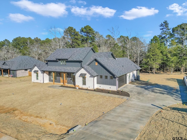 modern inspired farmhouse featuring covered porch, a front lawn, and a garage