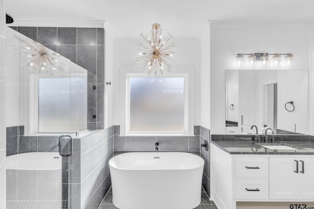 bathroom featuring tile patterned flooring, vanity, shower with separate bathtub, an inviting chandelier, and tile walls