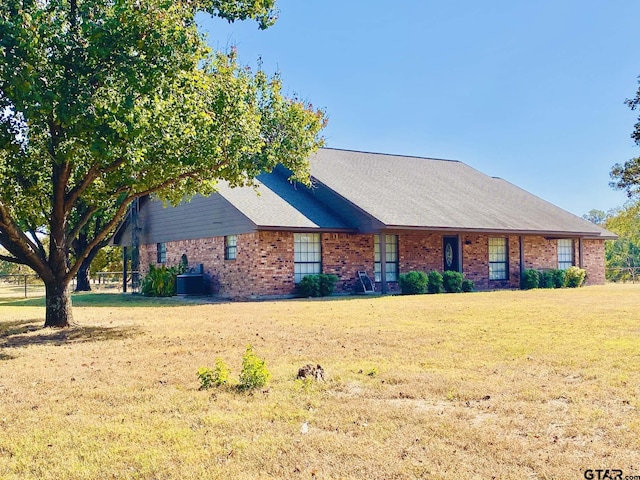 view of front of home with central air condition unit and a front yard