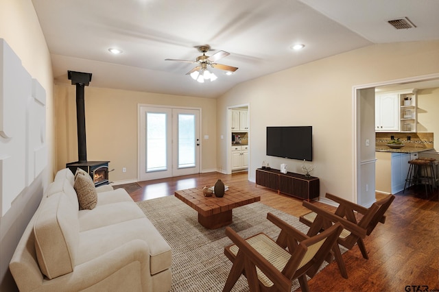 living room featuring dark hardwood / wood-style flooring, lofted ceiling, a wood stove, and ceiling fan