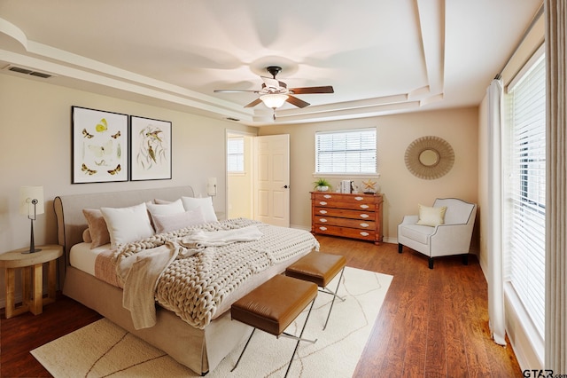 bedroom with a raised ceiling, ceiling fan, and dark hardwood / wood-style floors