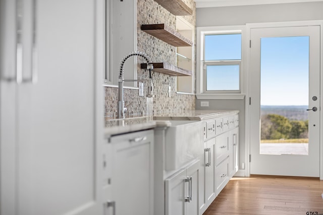 kitchen featuring white cabinets, light hardwood / wood-style floors, and tasteful backsplash