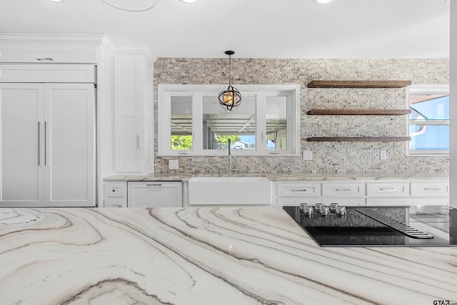 kitchen featuring a wealth of natural light, hanging light fixtures, sink, and paneled built in fridge