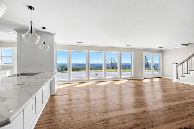 unfurnished living room featuring hardwood / wood-style floors, french doors, and crown molding