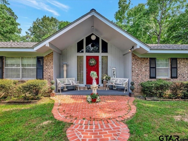 doorway to property with brick siding, board and batten siding, and a lawn