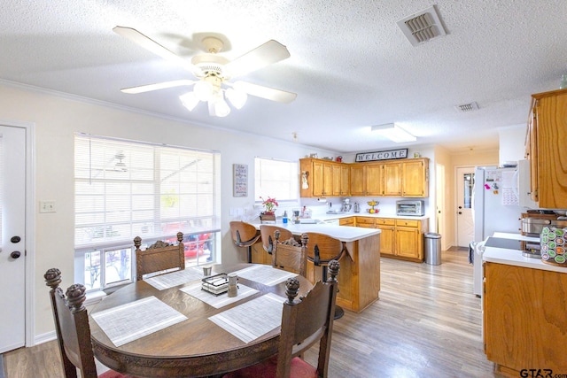 2505 W Gay Ave, Gladewater, TX 75647 - dining space featuring a textured ceiling, light wood finished floors, healthy amount of natural light, ceiling fan, and crown molding