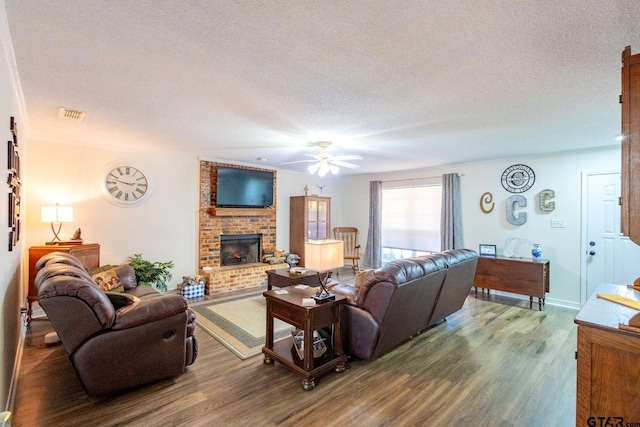2505 W Gay Ave, Gladewater, TX 75647 - living room featuring a textured ceiling, wood finished floors, a brick fireplace, ceiling fan, and baseboards