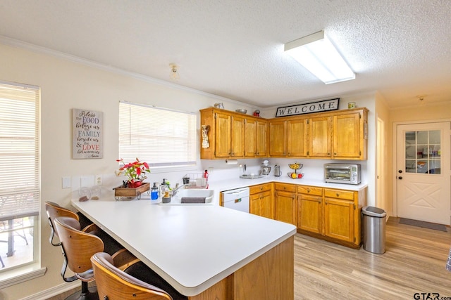2505 W Gay Ave, Gladewater, TX 75647 - kitchen with white dishwasher, light countertops, a sink, a peninsula, and ornamental molding