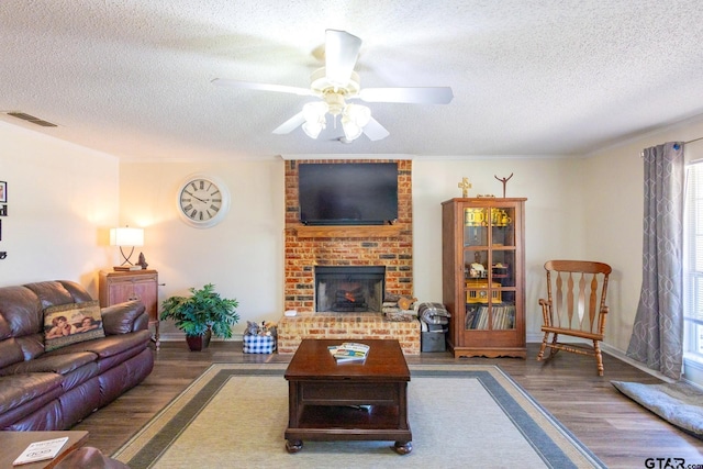 2505 W Gay Ave, Gladewater, TX 75647 - living room with a textured ceiling, wood finished floors, a ceiling fan, a brick fireplace, and baseboards