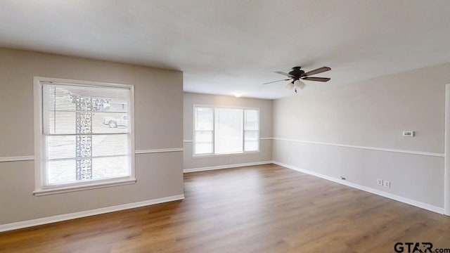 spare room with baseboards, ceiling fan, and wood finished floors