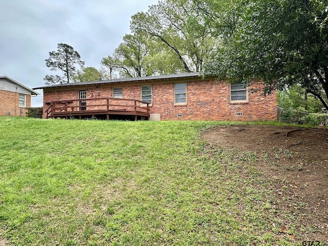 back of property with a wooden deck, brick siding, and a lawn