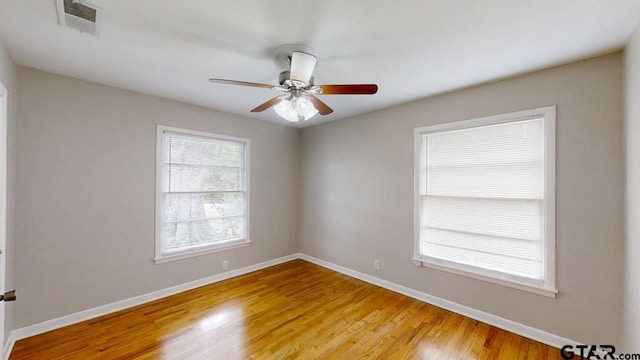 empty room featuring baseboards, visible vents, light wood-style flooring, and ceiling fan