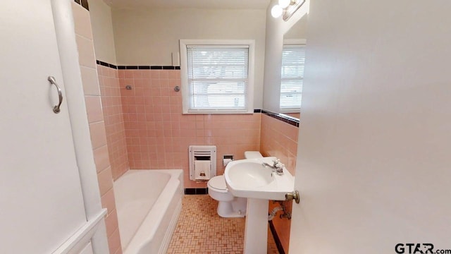 bathroom featuring tile walls, toilet, a sink, heating unit, and shower / tub combination