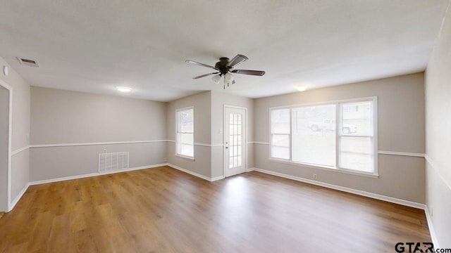 unfurnished room with ceiling fan, visible vents, and wood finished floors