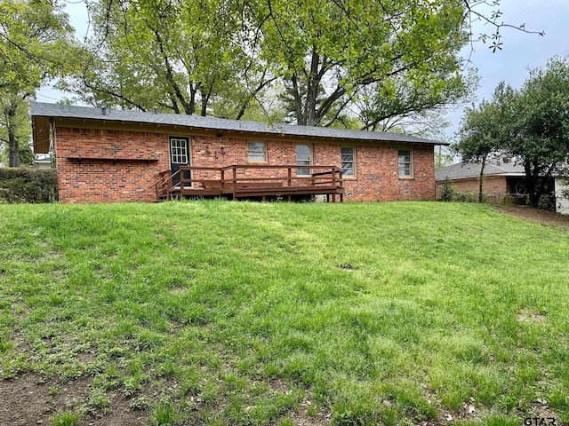 back of house with brick siding, a wooden deck, and a yard